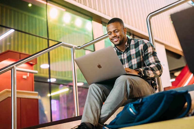 Student on laptop on social stairs