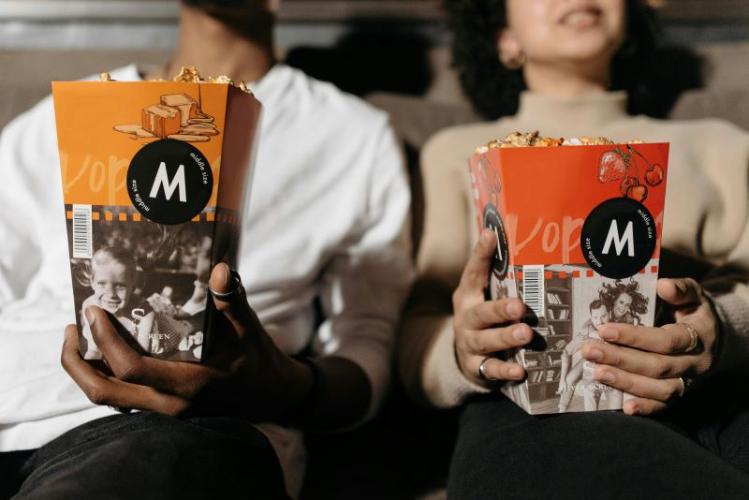 two people in a movie theatre holding popcorn