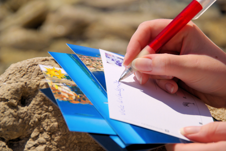 a person writing on a postcard