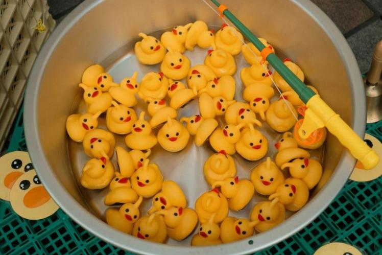 small yellow rubber ducks in a bowl with a fishing rod