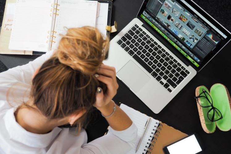 woman sitting at a laptop with her head in her hands