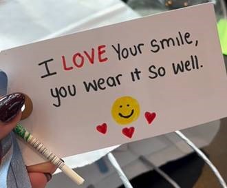 image of a piece of paper with the words 'I LOVE your smile, you wear it so well.' with a drawing of a yellow smiley face and three red hearts